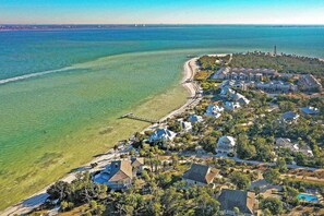 A coastal residential area with houses, a pier, and a clear view of the ocean.