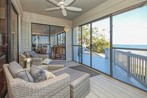 A covered outdoor seating area with wicker furniture and a view of the ocean. - Waterside Retreat with Pool, Steps to Lighthouse (Sanibel)