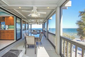 A covered outdoor area with a dining table and chairs, a kitchen area with a counter, and a view of the ocean. - Waterside Retreat with Pool, Steps to Lighthouse (Sanibel)