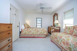 A bedroom with two beds, a ceiling fan, a dresser, a mirror, and a window with blinds. - Waterside Retreat with Pool, Steps to Lighthouse (Sanibel)