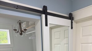 A walk-in closet with open shelving, a sliding door, and a chandelier.