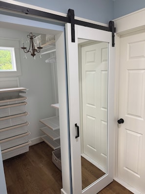 A walk-in closet with open shelving, a sliding door, and a chandelier.