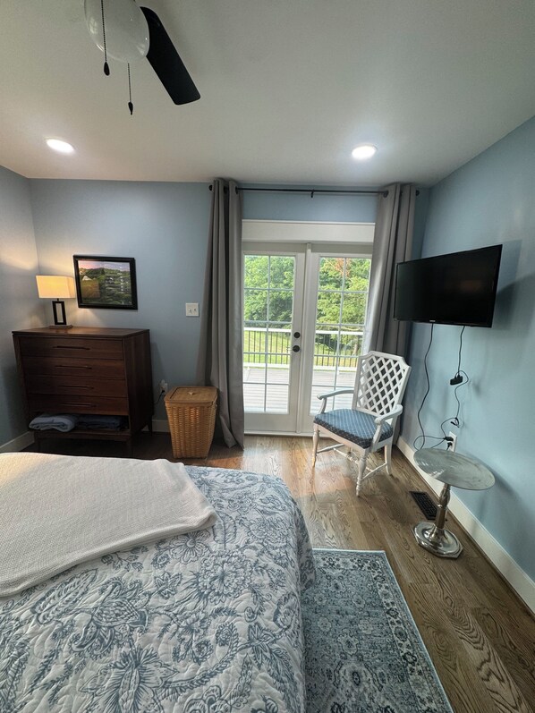 A bedroom with a bed, a chair, a TV, and a balcony.