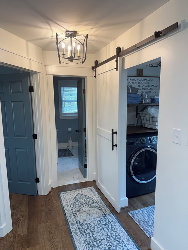 A laundry room with a washing machine, a drying rack, and a motivational quote on the wall.