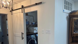 A laundry room with a washing machine, a drying rack, and a motivational quote on the wall.