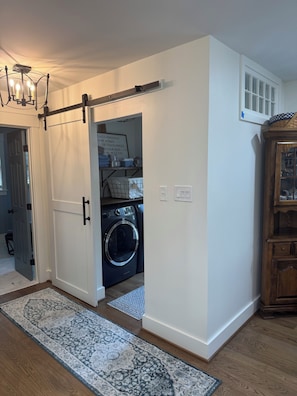 A laundry room with a washing machine, a drying rack, and a motivational quote on the wall.