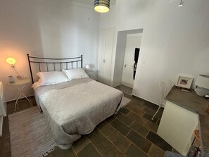 Un dormitorio con cama, mesitas de noche, una lámpara, un marco de cuadros y un armario.