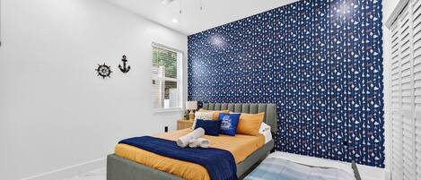 A bedroom with a bed, a bench, a ceiling fan, and a window with blinds.