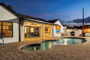 A residential property with a swimming pool, a patio area, and a large mural on the exterior wall.