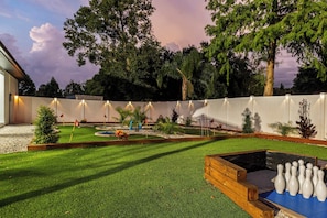 A backyard with a lawn, a wooden play structure, and a small pool.