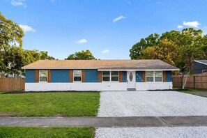 Une maison de plain-pied avec un porche à l’avant, un garage et une allée.