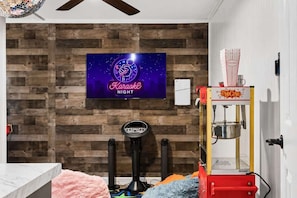 A room with a wooden wall, a neon sign for Karaoke Night, a popcorn machine, and exercise equipment. - Heated Pool • Golf • Fire Pit • 15 Min To Beach (Seminole)