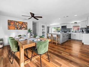 A modern kitchen with a dining area, wooden flooring, and a ceiling fan. - Heated Pool • Golf • Fire Pit • 15 Min To Beach (Seminole)