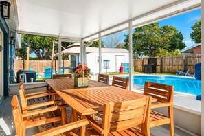 A covered patio area with a wooden table and chairs, a pool, and a white mobile home in the background. - Heated Pool • Golf • Fire Pit • 15 Min To Beach (Seminole)