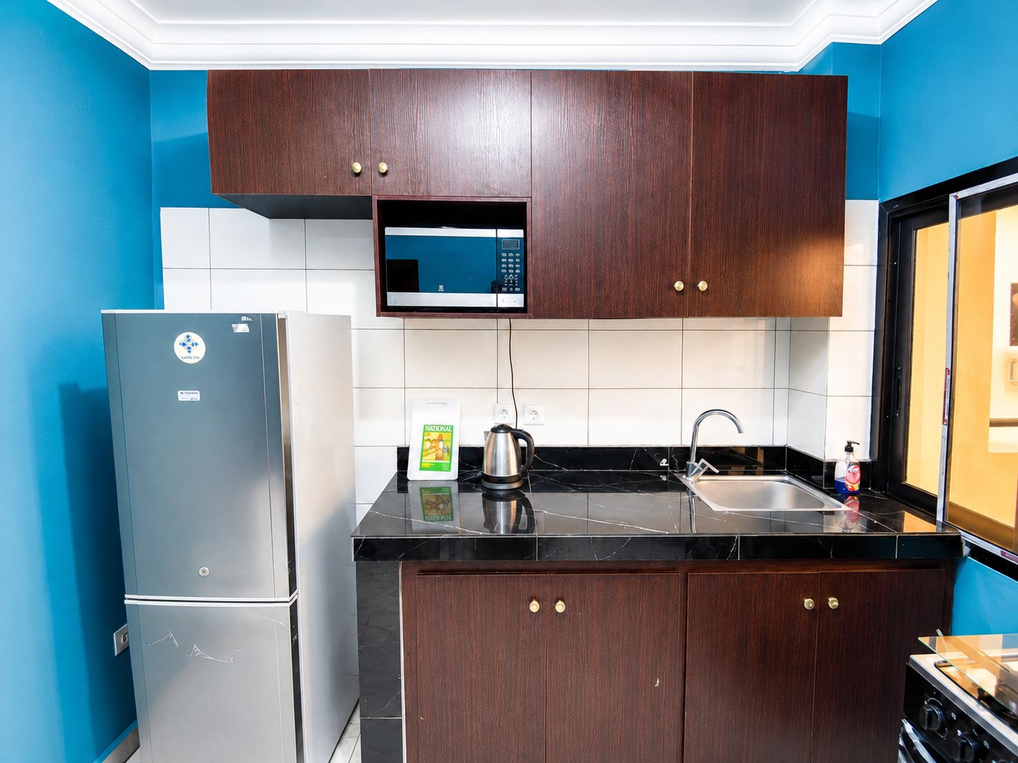 A kitchen with a refrigerator, microwave, sink, and stove.