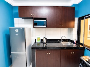 A kitchen with a refrigerator, microwave, sink, and stove.