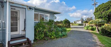 A single-story building with a gravel driveway leading to a front door.