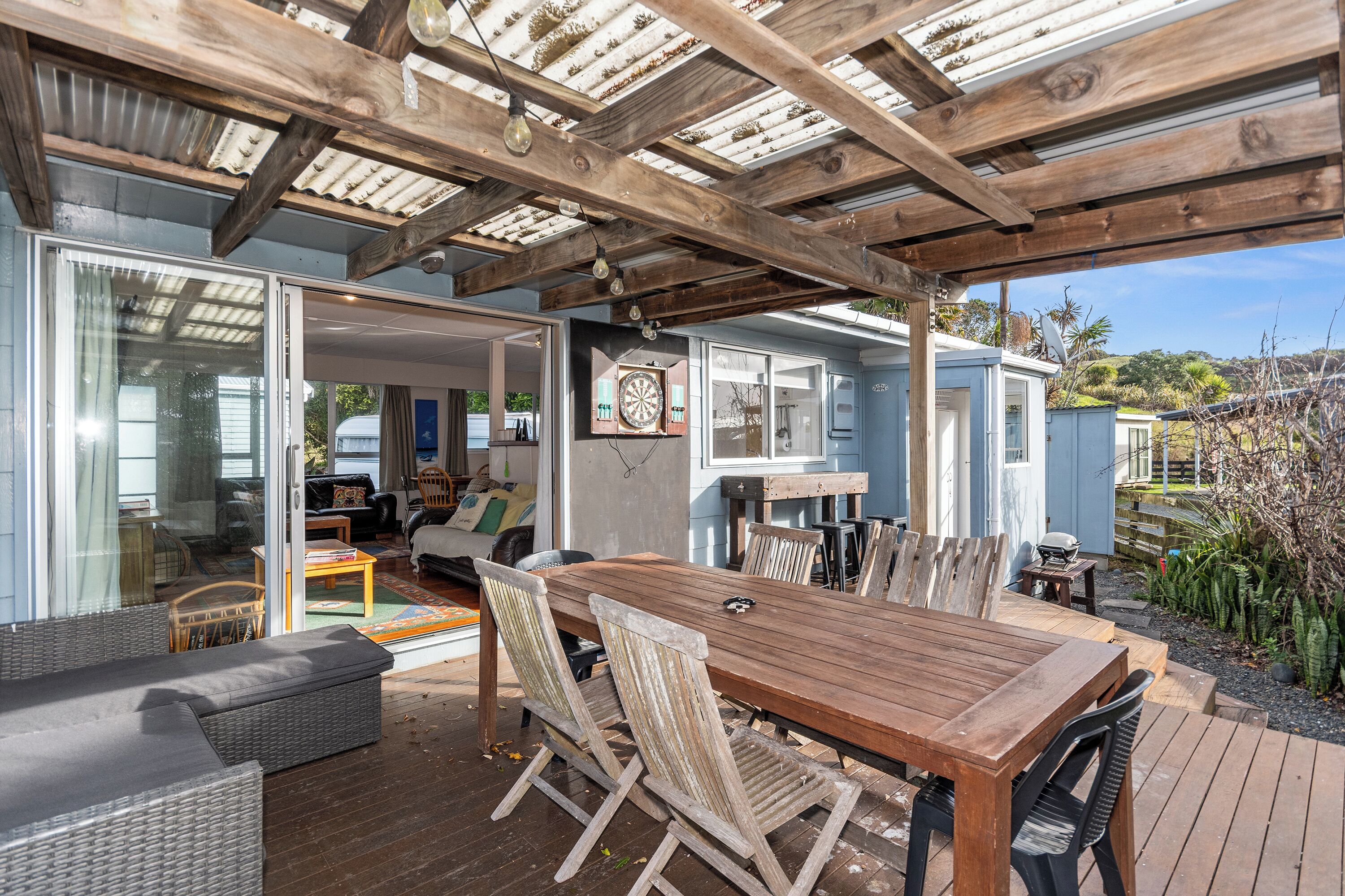 A covered outdoor patio with a wooden table and chairs, a sofa, and a dining area.