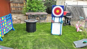Un patio trasero con una chimenea, un blanco para tiro y una zona de juegos infantiles.