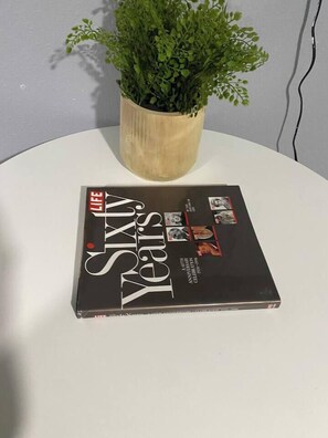 A book titled 'LIFE SIXTY Years' on a white surface with a potted plant behind it.