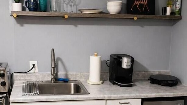 Una cocina compacta con pileta, cafetera y refrigerador.