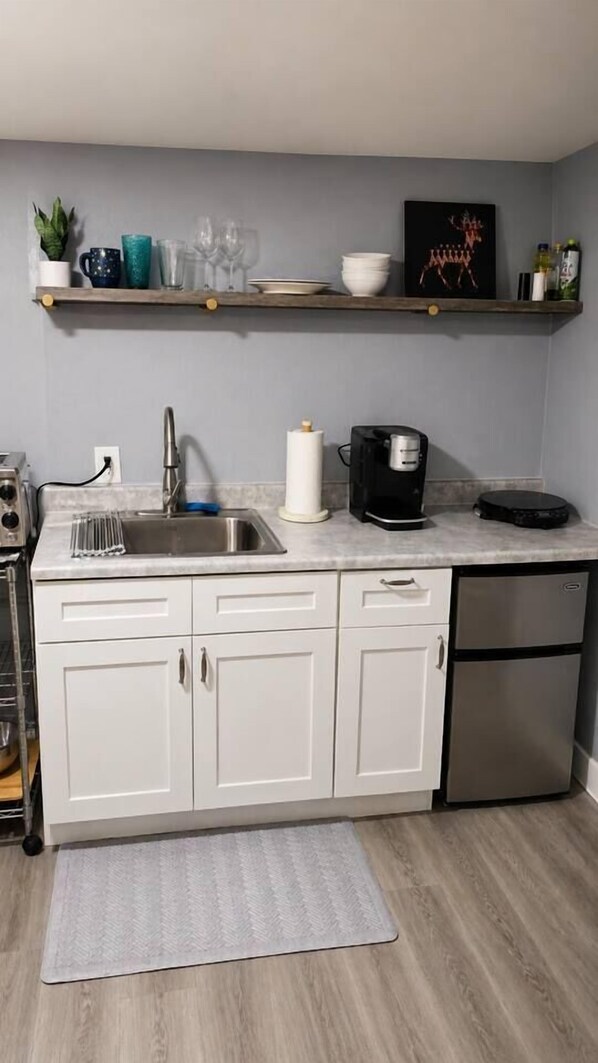 A compact kitchen with a sink, a coffee maker, and a refrigerator.