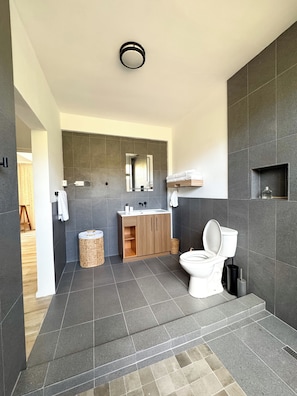 A modern bathroom with a toilet, sink, and mirror. - Luxury 2 Bedroom Condo 5 mins from UVF (Morne Caillandre)