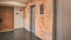 A hallway with a wooden door, an elevator, and a wall-mounted sign. - Casa Mexico (Ciudad de México)