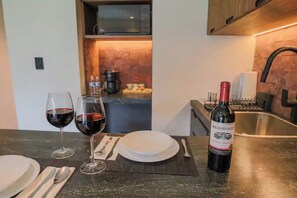Una encimera de cocina con dos copas de vino, una botella y un plato.