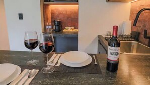 A kitchen counter with two wine glasses, a bottle of wine, and a white plate. - Casa Mexico (Ciudad de México)
