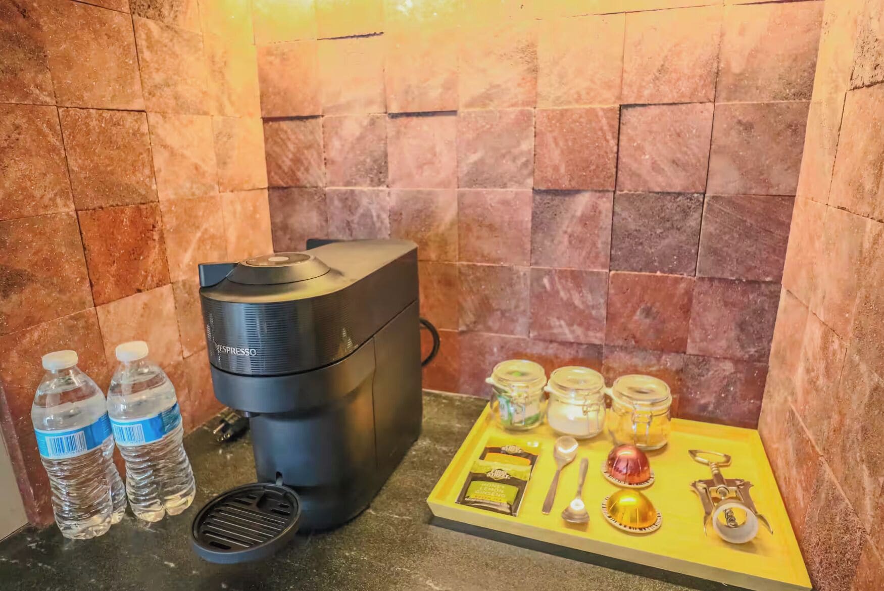 Una macchina da caffè, due bottiglie d'acqua e un vassoio con accessori per preparare il caffè su un piano di lavoro.