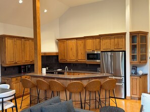 A modern kitchen with wooden cabinets, stainless steel appliances, and a central island with bar stools. - Ski-In/Ski-Out Luxury Townhome Renovated 2026 Bunk Room + Game Level (Beaver Creek)