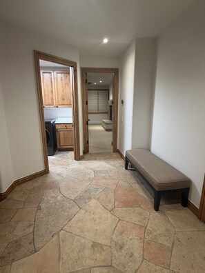 A hallway with a stone floor, wooden cabinets, and a bench. - Ski-In/Ski-Out Luxury Townhome Renovated 2026 Bunk Room + Game Level (Beaver Creek)