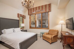 Ein Hotelzimmer mit einem Bett, einem Sessel, einem Fernseher und einer Kandelaber.
