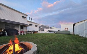 A backyard with a fire pit, a covered grill, and a boat docked outside. - 3BR 2B Short/Long term Available! Ventnor Heights Home/Back Yard, Walk to Beach! (Ventnor City)