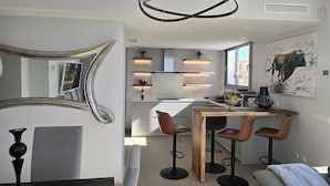 Een moderne keuken met inbouwapparatuur, een eetgedeelte met krukken en een grote spiegel.