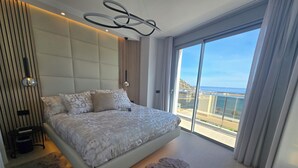 Een moderne slaapkamer met een groot bed, uitzicht op zee en een balkon.