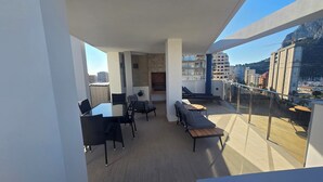 Een modern balkon met een eethoek, zitgedeelte en uitzicht op de stad.