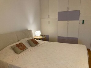 Ein Schlafzimmer mit einem großen Bett, einem Kleiderschrank und einem Nachttisch mit Lampe.