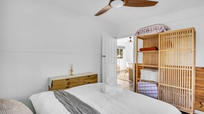 A bedroom with a bed, a wooden wardrobe, a nightstand, and a ceiling fan. - Camel Rock Cottage - Beauty Point 33 (Wallaga Lake)