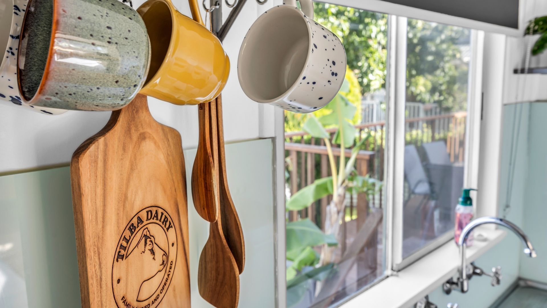 Een keuken met hangend houten keukengerei en keramische mokken.