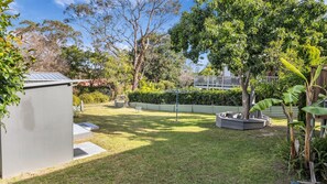 A well-maintained backyard with a lawn, a small shed, and a variety of trees and shrubs. - Camel Rock Cottage - Beauty Point 33 (Wallaga Lake)
