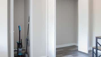 Una habitación con un armario cerrado, un aspirador y una escoba.