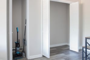 Una habitación con un armario cerrado, un aspirador y una escoba.