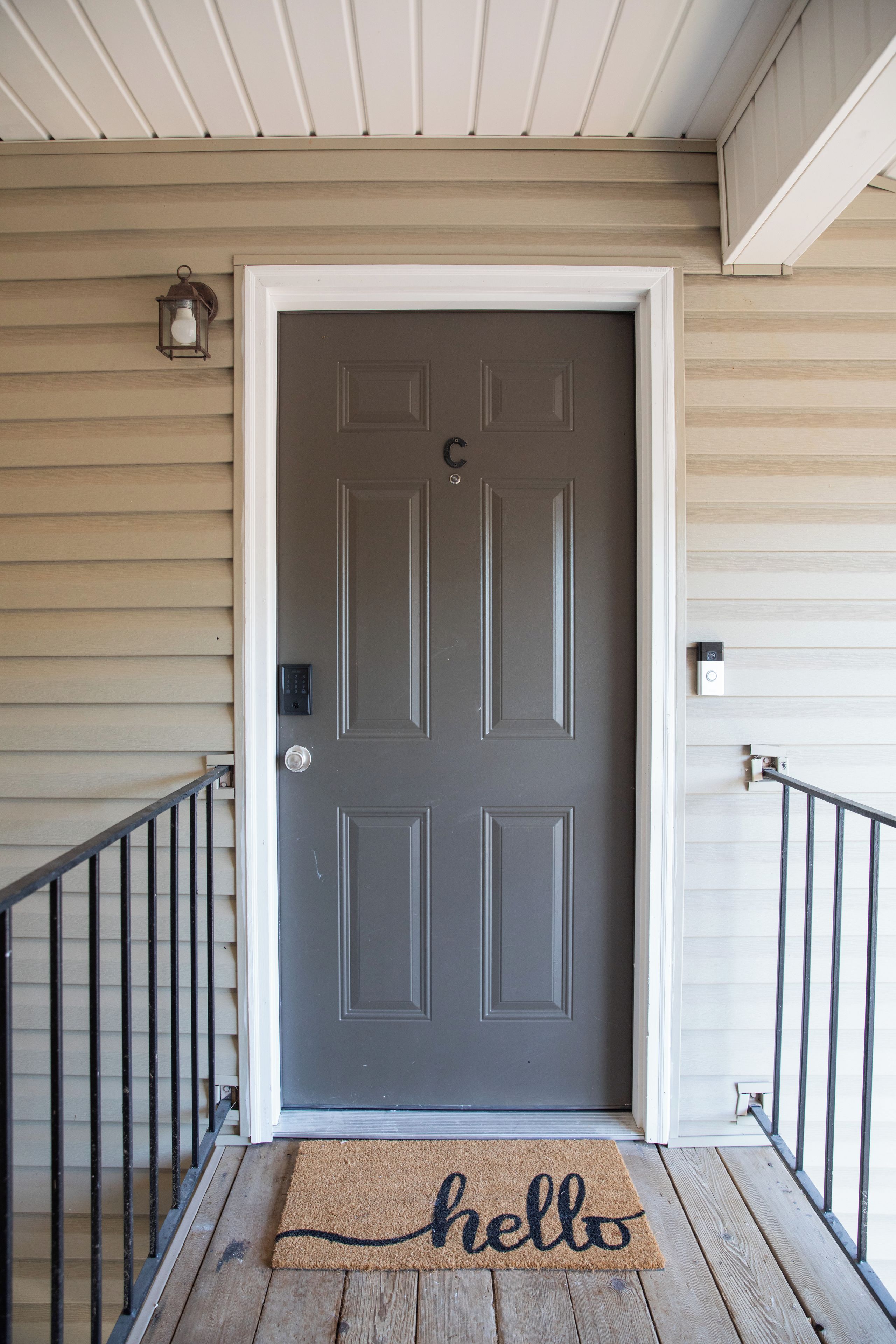 A front door with a doormat, a mailbox, and a security camera.