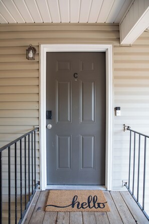 Puerta principal con felpudo, buzón y cámara de seguridad.
