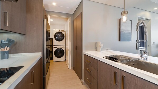 A modern kitchen with a built-in oven, a sink with a stainless steel faucet, and a countertop with a dish rack.
