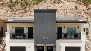 A two-story building with a balcony, a garage, and a number sign.
