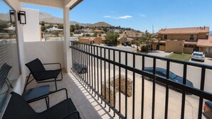 A balcony with a view of a residential area, a stone planter, and a parked car.