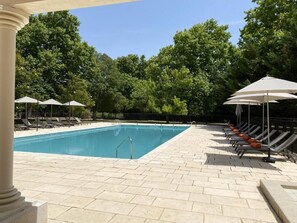 A swimming pool with lounge chairs and umbrellas, surrounded by trees. - Domaine de la Reynaude (Aurons)
